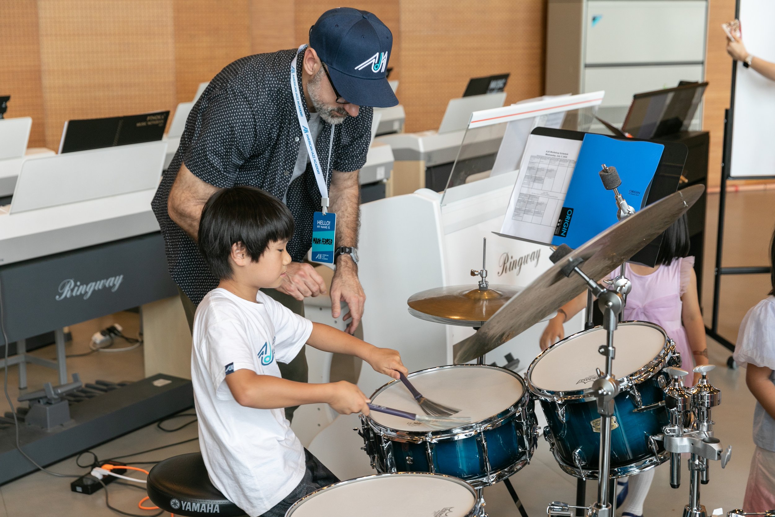 AJA instructor teaching a student drums in the classroom